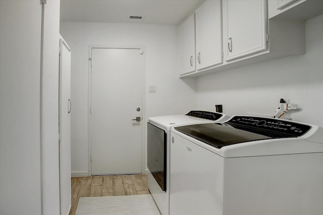 washroom with cabinet space, light wood-type flooring, and washing machine and clothes dryer