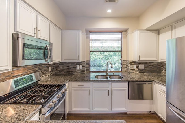 737 Davis Rd, League City, TX 77573 - kitchen featuring dark stone countertops, white cabinets, a sink, stainless steel appliances, and decorative backsplash