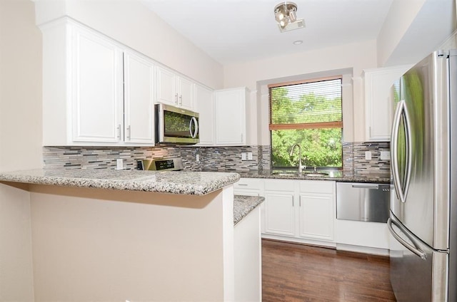 737 Davis Rd, League City, TX 77573 - kitchen with a peninsula, white cabinets, light stone counters, a sink, and stainless steel appliances