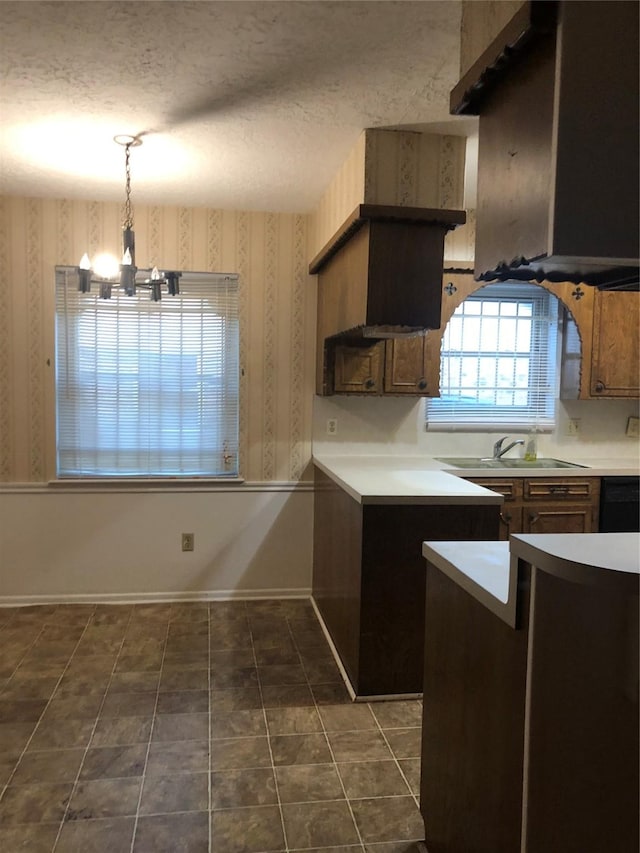 14407 Duncannon Dr, Houston, TX 77015 - kitchen featuring a textured ceiling, a sink, wallpapered walls, a notable chandelier, and hanging light fixtures