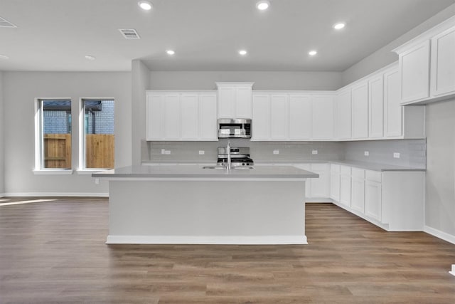 21026 Seneca Bluff Ln, Cypress, TX 77433 - kitchen with appliances with stainless steel finishes, a kitchen island with sink, backsplash, a sink, and recessed lighting