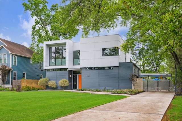 contemporary home with a front lawn, fence, and concrete driveway