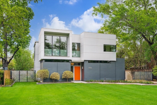contemporary house featuring a front yard, fence, and stucco siding