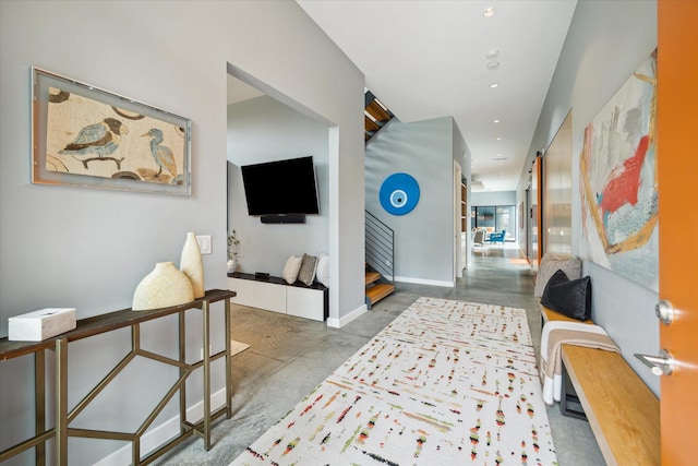 hall featuring concrete floors, baseboards, stairway, and recessed lighting