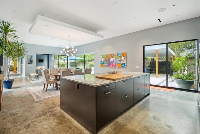 kitchen with a center island, an inviting chandelier, modern cabinets, open floor plan, and concrete flooring