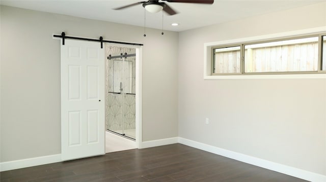 9121 Fordshire Dr, Houston, TX 77025 - unfurnished bedroom with multiple windows, baseboards, dark wood finished floors, and a barn door