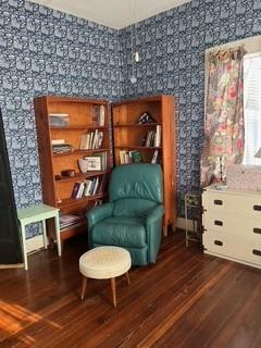 living area featuring dark wood-type flooring and wallpapered walls