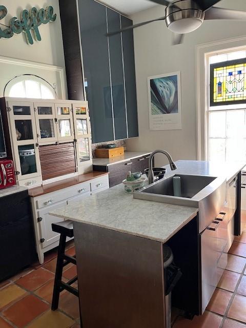 kitchen featuring white cabinets, tile patterned floors, light countertops, and a sink