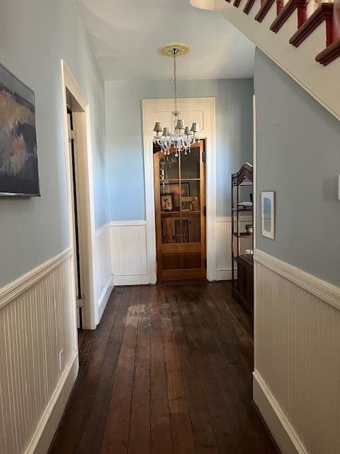interior space featuring an inviting chandelier, wainscoting, and dark wood-style floors