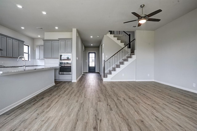 2904 Apple Rose, Katy, TX 77493 - kitchen with stainless steel appliances, a healthy amount of sunlight, light wood-style flooring, open floor plan, and gray cabinetry
