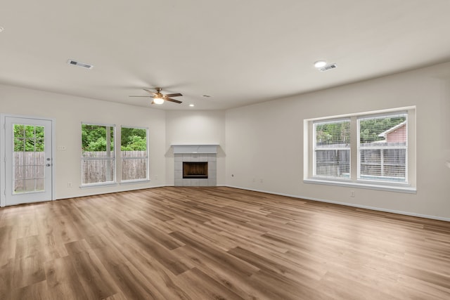 1069 Shadow Glenn Dr, Conroe, TX 77301 - unfurnished living room featuring a tile fireplace, visible vents, wood finished floors, and ceiling fan