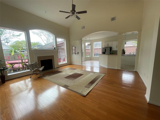 4311 Lakeside Meadow Dr, Missouri City, TX 77459 - unfurnished living room with arched walkways, ceiling fan, decorative columns, and light wood finished floors