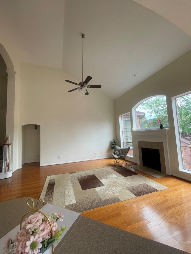 4311 Lakeside Meadow Dr, Missouri City, TX 77459 - living area with arched walkways, high vaulted ceiling, wood finished floors, and a tiled fireplace