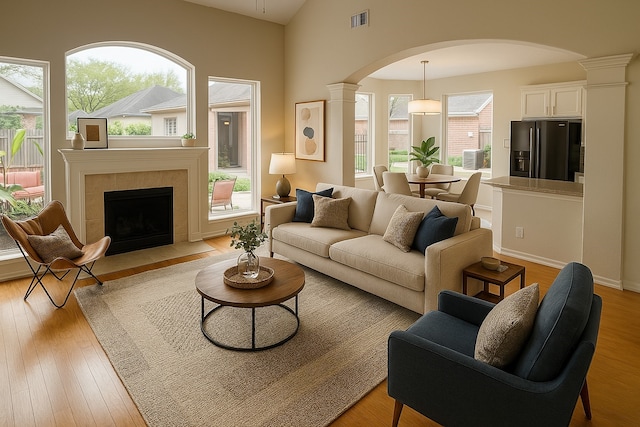 4311 Lakeside Meadow Dr, Missouri City, TX 77459 - living area featuring decorative columns, arched walkways, light wood finished floors, visible vents, and a tiled fireplace
