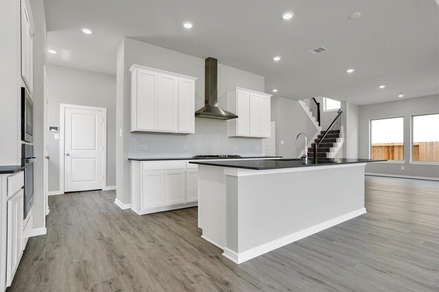 2916 Apple Rose, Katy, TX 77493 - kitchen featuring light wood-style flooring, dark countertops, visible vents, wall chimney range hood, and appliances with stainless steel finishes