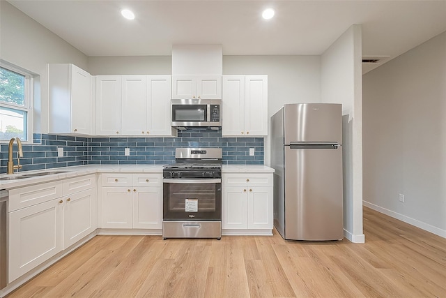 kitchen featuring light wood finished floors, light countertops, a sink, and stainless steel appliances