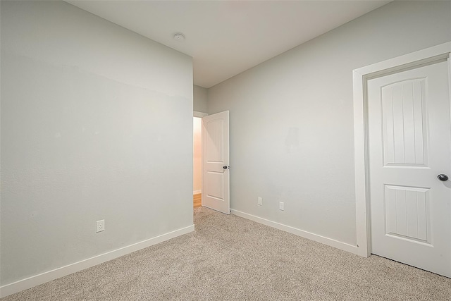 empty room featuring light carpet and baseboards