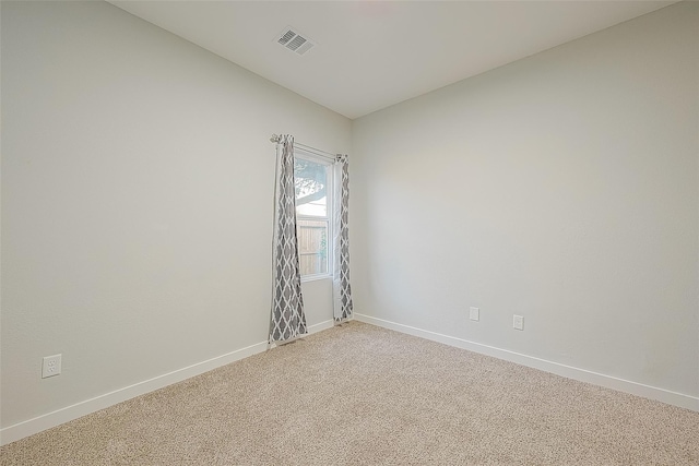 spare room featuring light colored carpet, visible vents, and baseboards