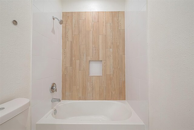 full bathroom with toilet, shower / bath combination, and a textured wall