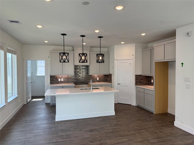 15854 Invergelder Dr, Atascocita, TX 77346 - kitchen featuring a sink, a kitchen island with sink, tasteful backsplash, baseboards, and light countertops