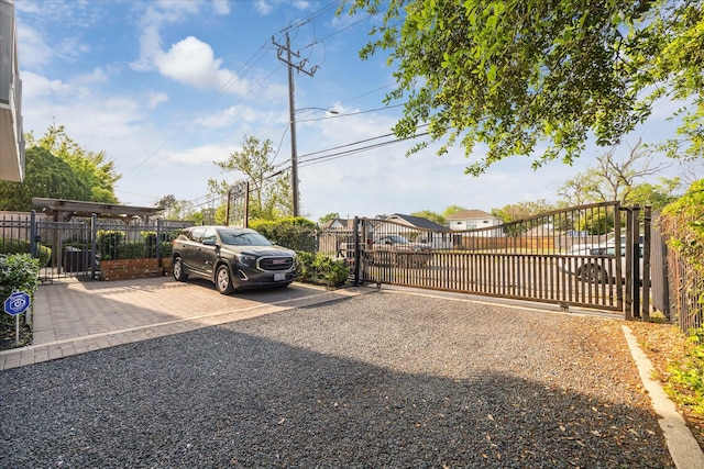 view of parking featuring fence and a gate