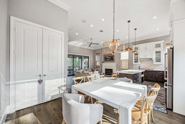 dining space with crown molding, dark wood-type flooring, and a fireplace
