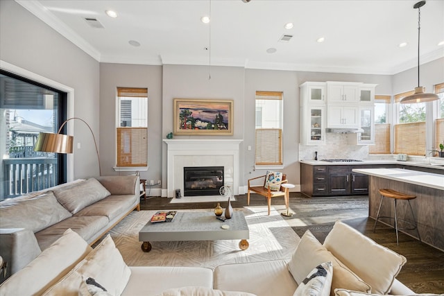 living room featuring crown molding, wood finished floors, visible vents, and a fireplace