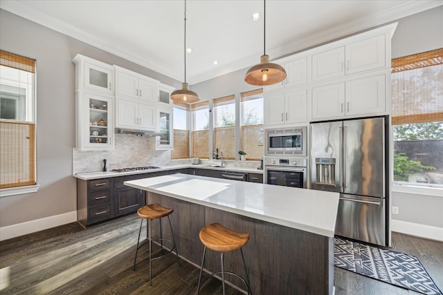 kitchen with white cabinets, stainless steel appliances, crown molding, and a healthy amount of sunlight