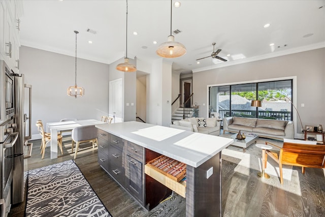 kitchen featuring light countertops, dark wood finished floors, ceiling fan with notable chandelier, a kitchen island, and visible vents