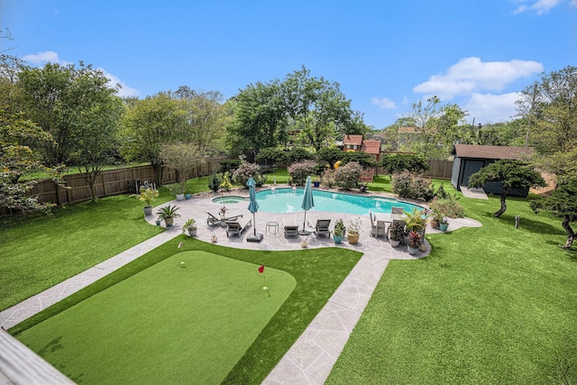 view of pool featuring a lawn, a patio area, a fenced in pool, an outdoor structure, and a fenced backyard