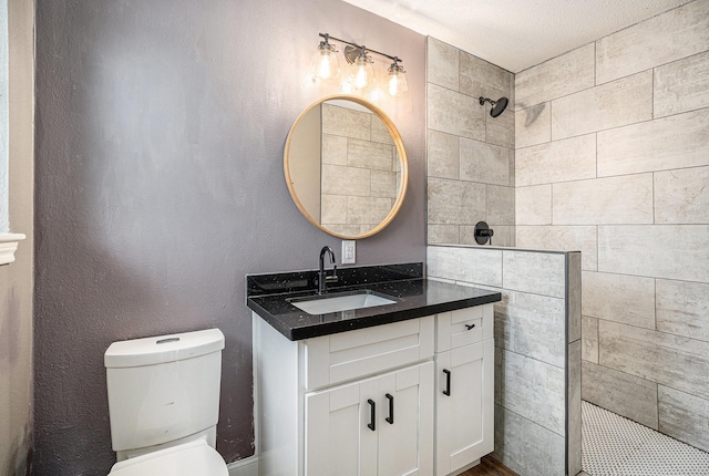 full bathroom featuring vanity, a walk in shower, and toilet
