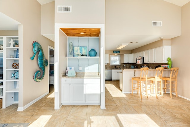 4406 Tampico Way, Galveston, TX 77554 - kitchen featuring visible vents, white cabinets, a kitchen bar, and stainless steel appliances
