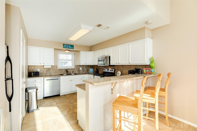 4406 Tampico Way, Galveston, TX 77554 - kitchen with tasteful backsplash, a sink, visible vents, a peninsula, and appliances with stainless steel finishes