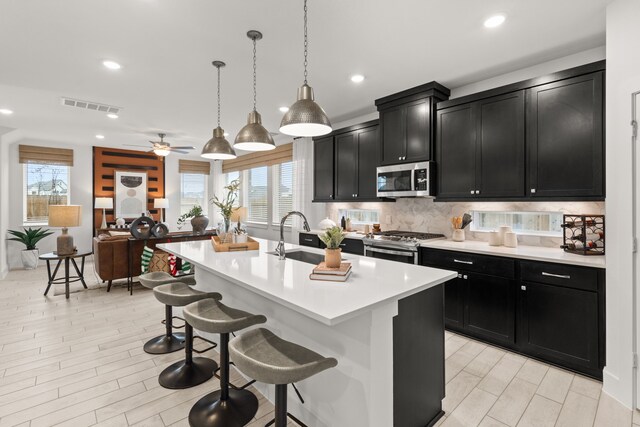15847 Invergelder Dr, Atascocita, TX 77346 - kitchen with a sink, a breakfast bar area, appliances with stainless steel finishes, dark cabinetry, and visible vents