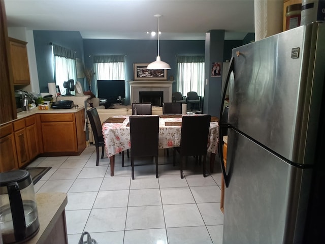 kitchen featuring freestanding refrigerator, light tile patterned floors, light countertops, and brown cabinets
