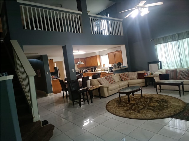 living room with a high ceiling, a ceiling fan, light tile patterned floors, and stairs