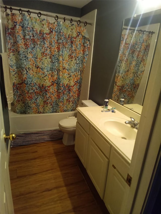 full bathroom featuring toilet, wood finished floors, shower / tub combo with curtain, and vanity