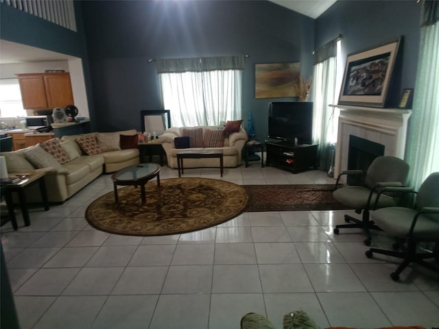 living room with a tiled fireplace, light tile patterned floors, and high vaulted ceiling
