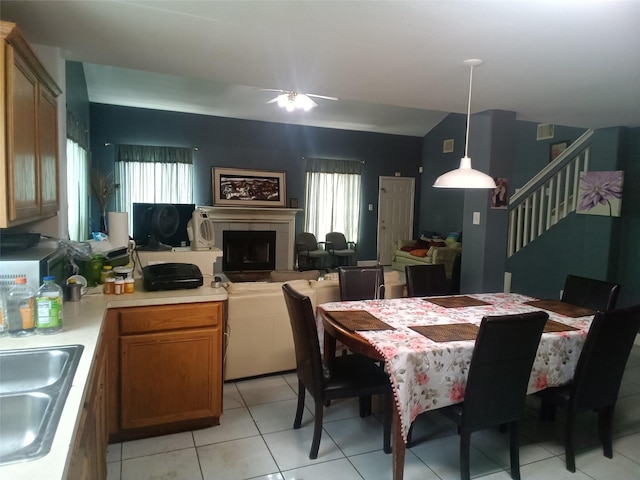 dining room featuring stairs, a fireplace, a healthy amount of sunlight, and a ceiling fan