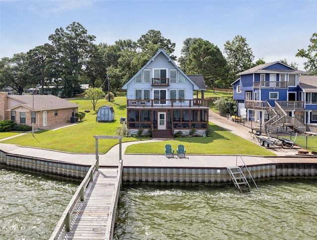 back of house with a lawn, a water view, a sunroom, and a balcony
