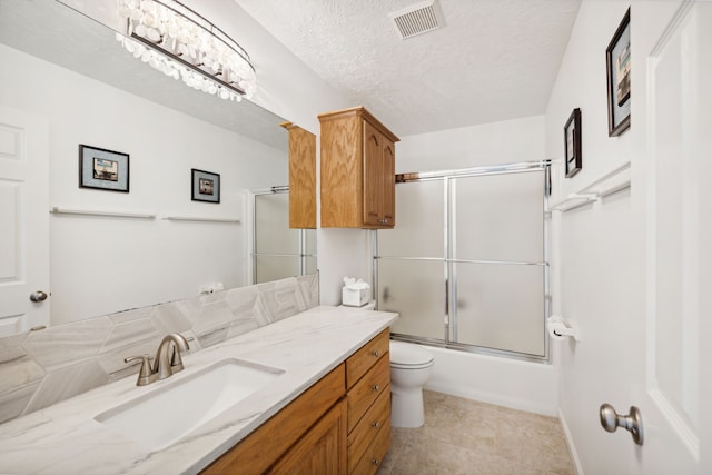 full bathroom with visible vents, vanity, toilet, bath / shower combo with glass door, and a textured ceiling