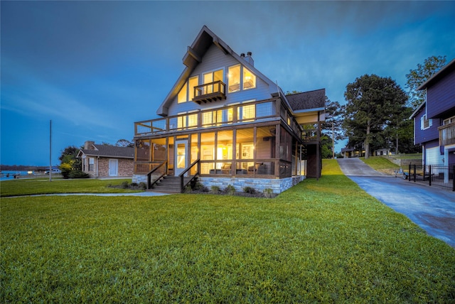 rear view of house featuring a lawn, covered porch, a chimney, and a balcony