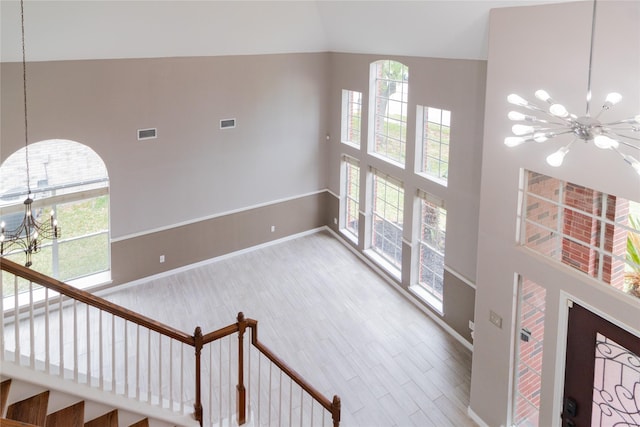 interior space featuring plenty of natural light, high vaulted ceiling, a chandelier, visible vents, and wood finished floors