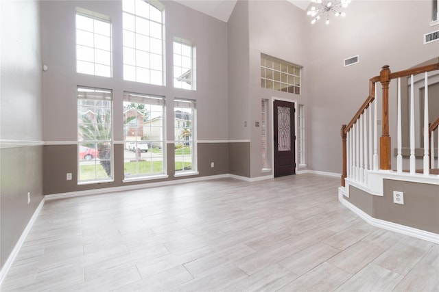 foyer featuring baseboards, stairs, visible vents, and a chandelier