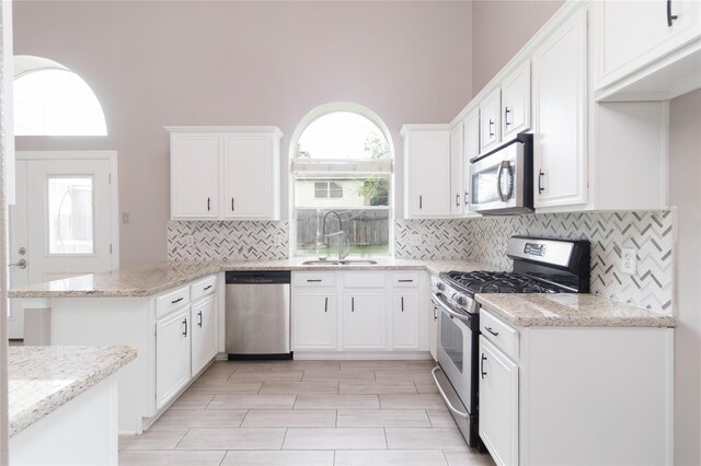 kitchen with white cabinetry, a sink, a peninsula, and appliances with stainless steel finishes