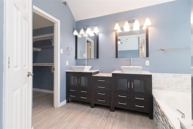 full bath with a relaxing tiled tub, a sink, and two vanities