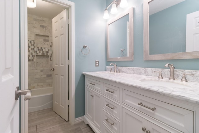 full bath featuring double vanity, a sink, shower / bathtub combination, and wood finish floors