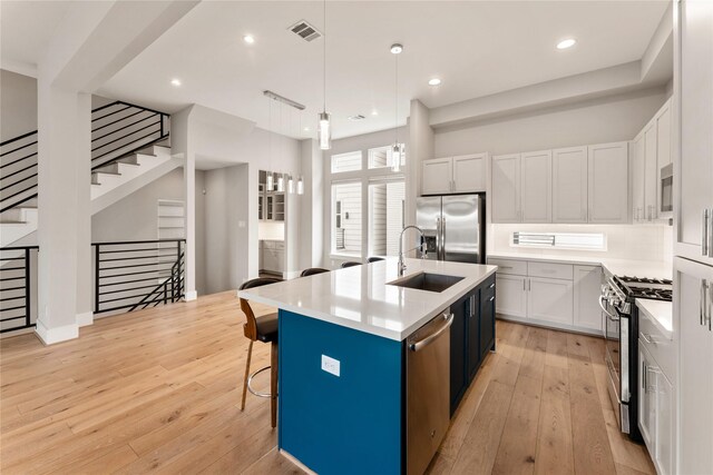 1033 Roberts St, Houston, TX 77003 - kitchen with stainless steel appliances, a sink, light wood-type flooring, a breakfast bar, and light countertops