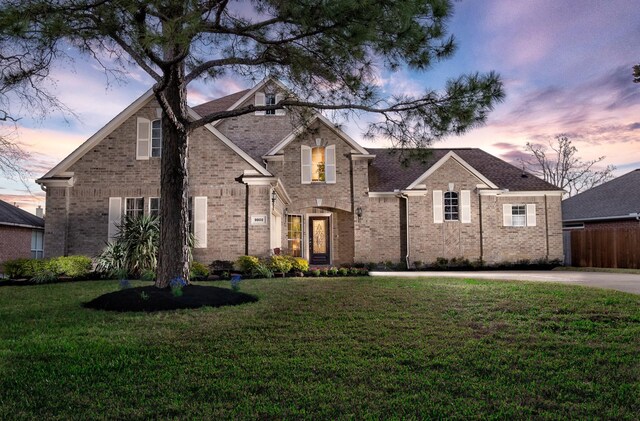 traditional-style house featuring brick siding, fence, and a front lawn