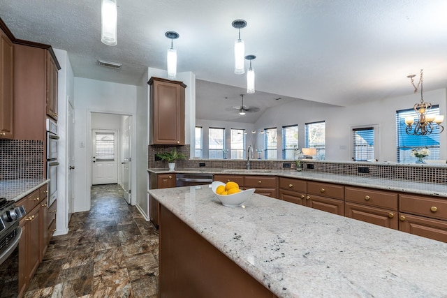 kitchen featuring a sink, tasteful backsplash, light stone countertops, appliances with stainless steel finishes, and visible vents